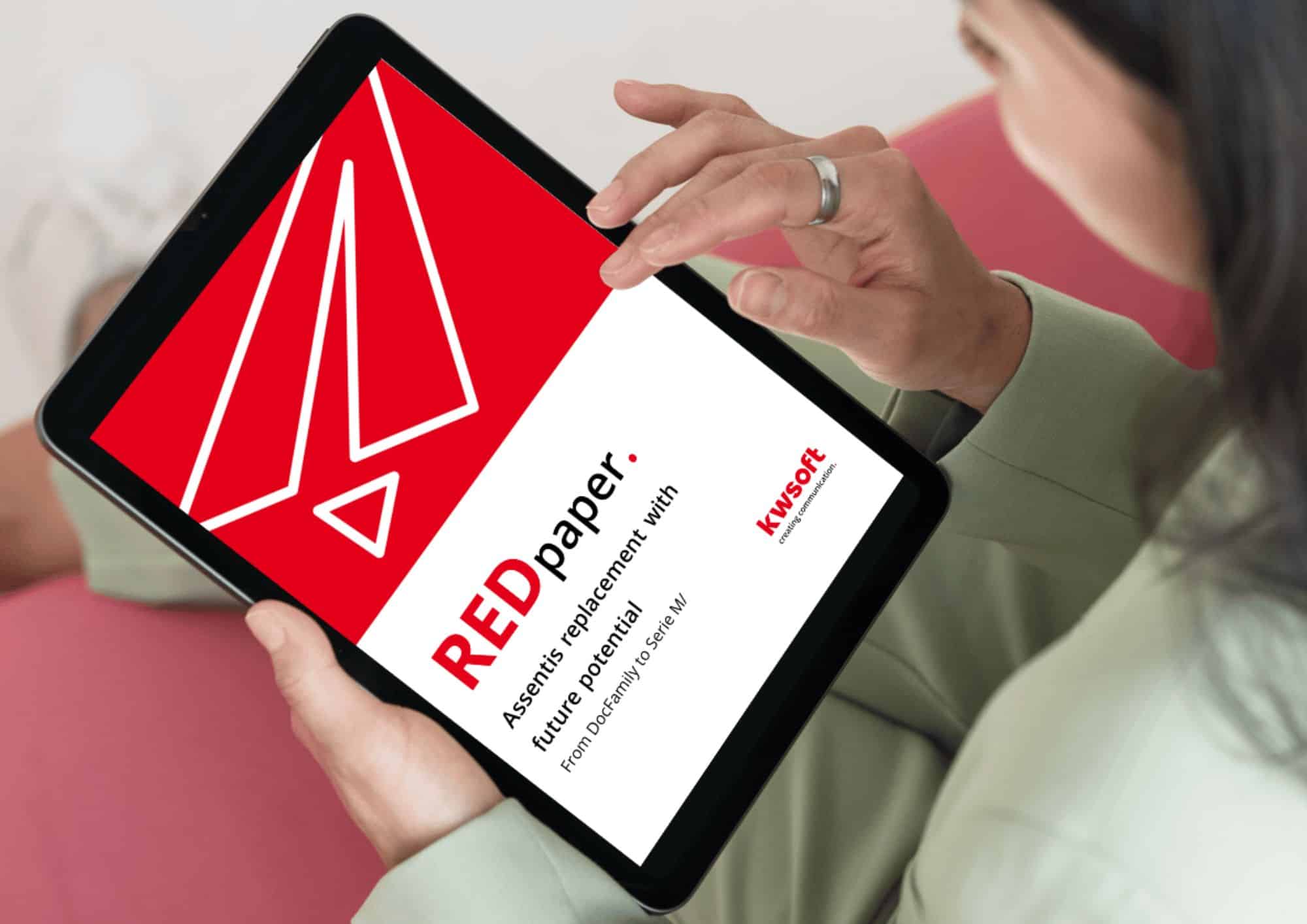 La imagen muestra una tableta sostenida por alguien que muestra la portada del REDpaper «Assentis Replacement».
